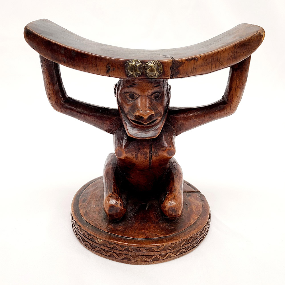 Wooden headrest with a base in the shape of a kneeling woman