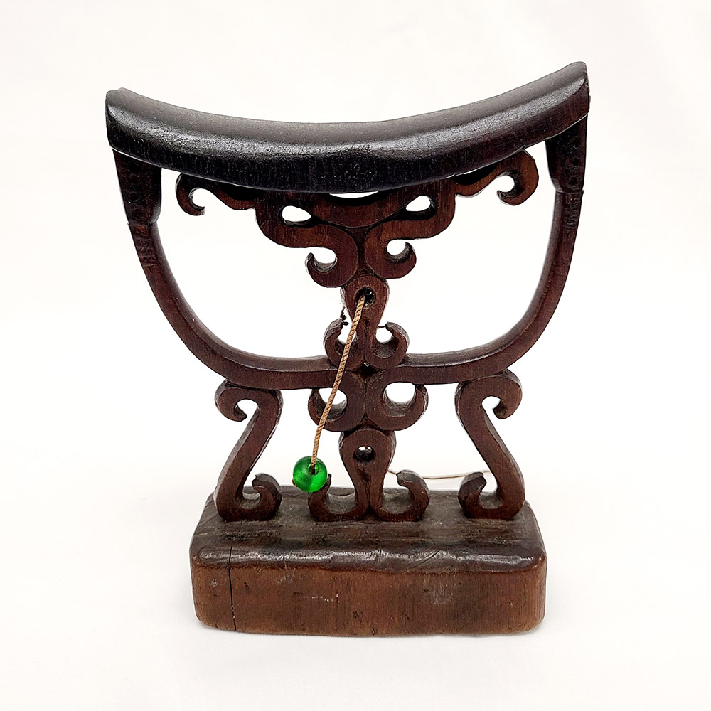 wooden headrest with scrollwork and a green bead