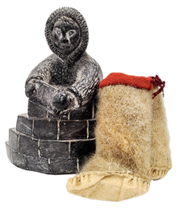 stone sculpture of figure building an igloo and miniature moccasins